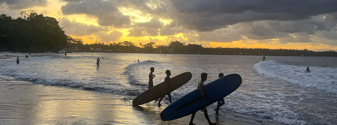 Alors que le soleil se couche sur la plage de Batukaras, deux surfeurs s'en vont chasser la vague.