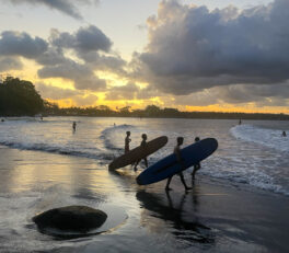 Alors que le soleil se couche sur la plage de Batukaras, deux surfeurs s'en vont chasser la vague.